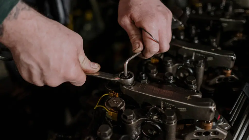 a mechanic using two hands to lock bolt on car engine