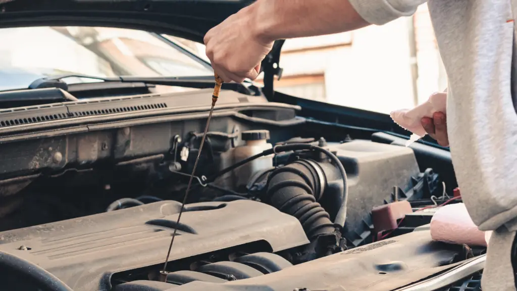 someone pulling the dipstick of car engine to check oil level