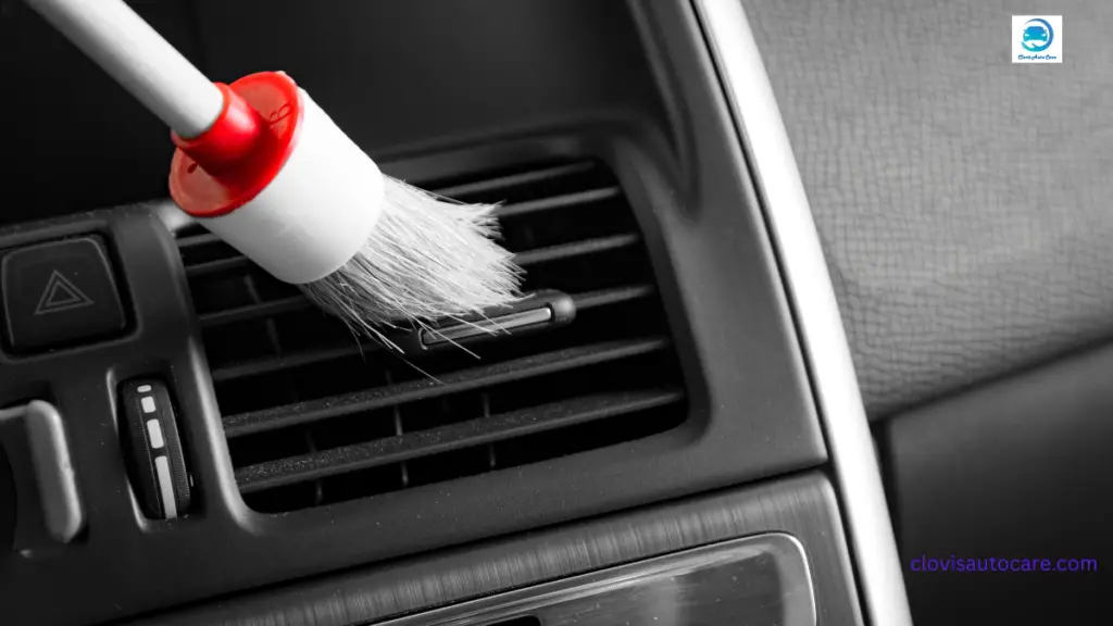 cleaning a car vent and dashboard with a brush