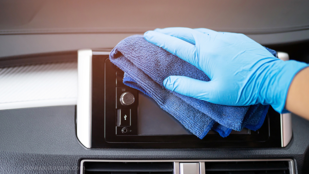 hand on blue glove with blow microfiber cloth cleaning car dashboard.