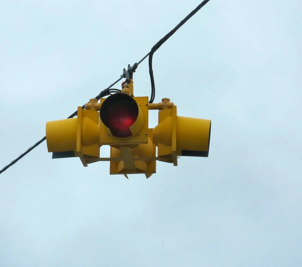 What Does A Flashing Yellow Light Mean? a yellow traffic light hanging on a string in the middle of the road.