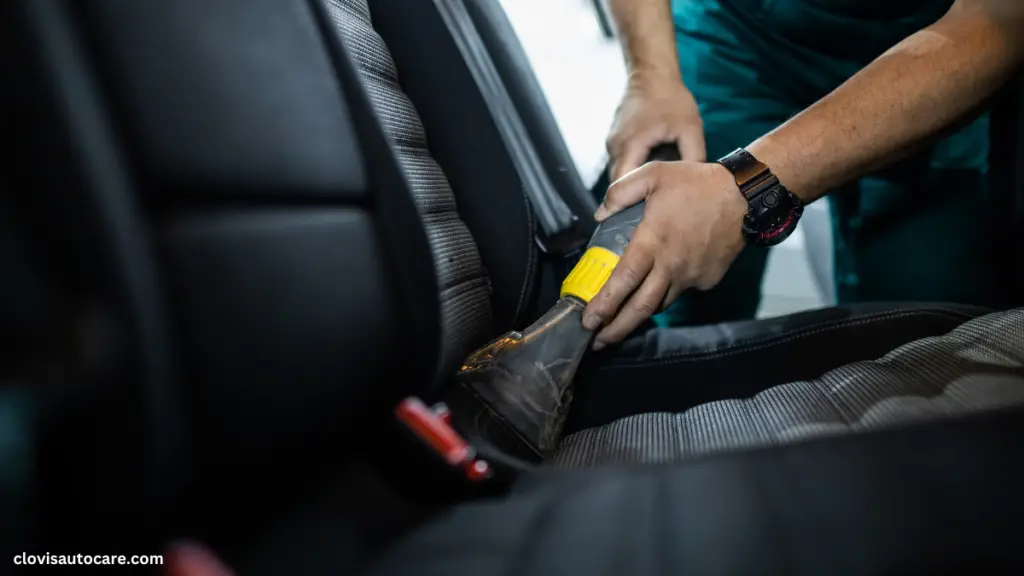 a person cleaning car seats with a vacuum cleaner 