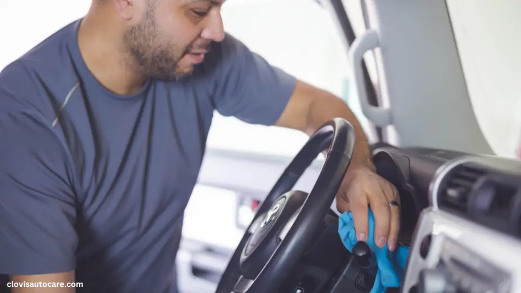 a man using a blue microfiber cloth to clean the interior of a car