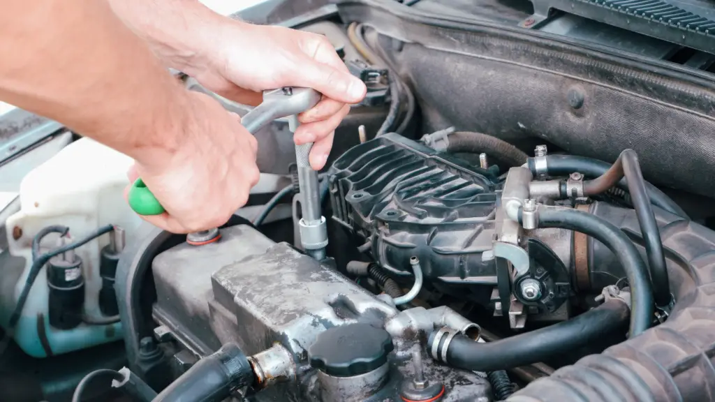 a man using tools to remove a spark plug from car engine