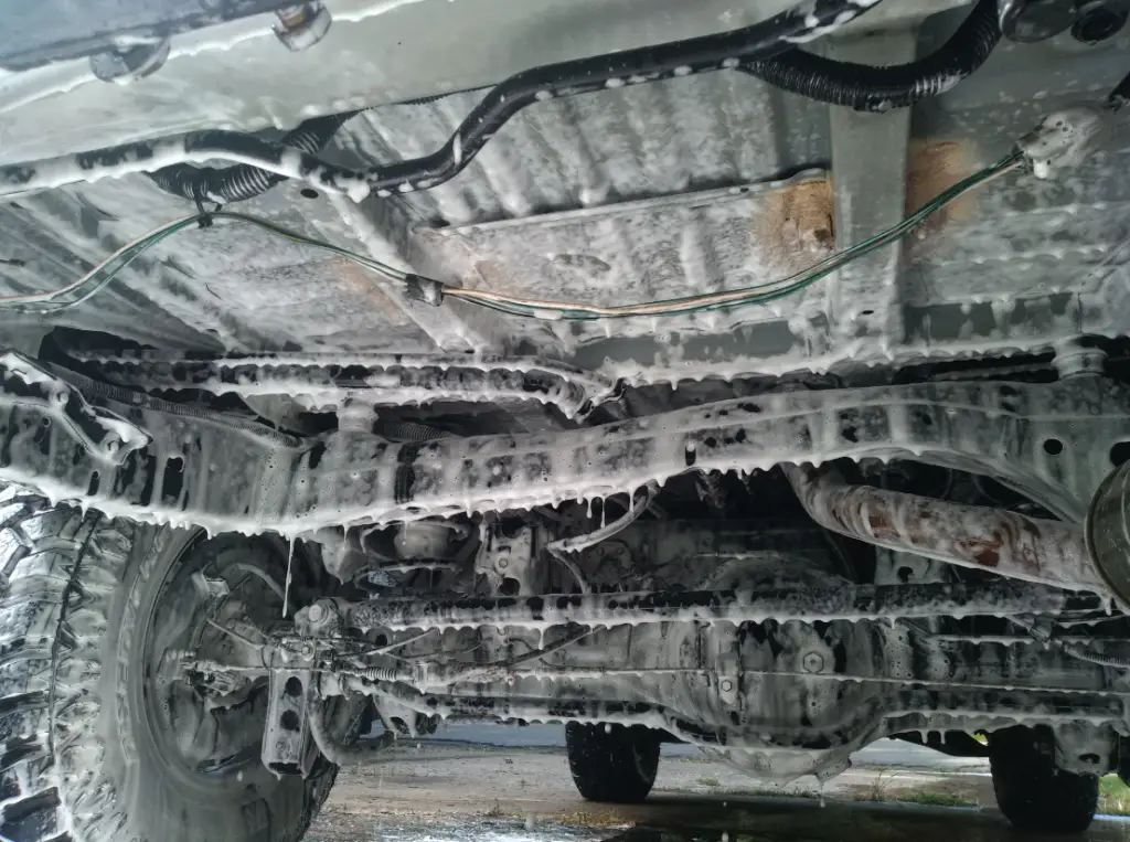 a photo of a car undergoing an undercarriage car wash.