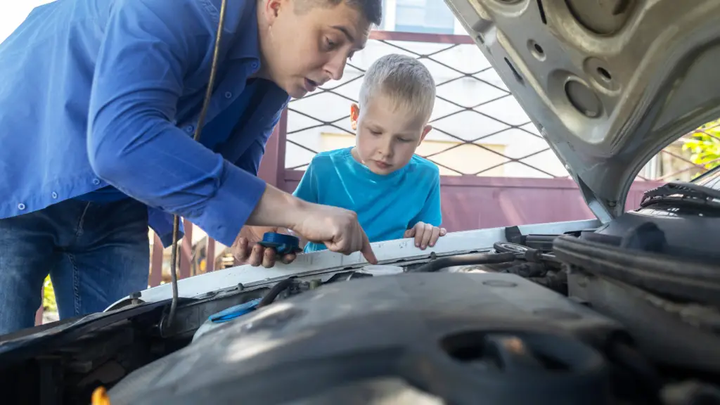 a father showing his son where to put coolant on a car engine